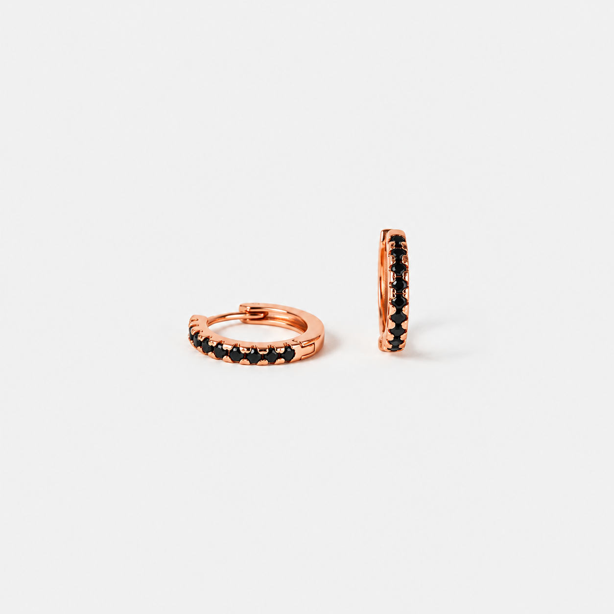 Rose gold hoop earrings with black gemstones on a white background